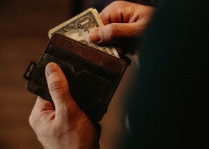 a man pulling a bill out of his leather wallet